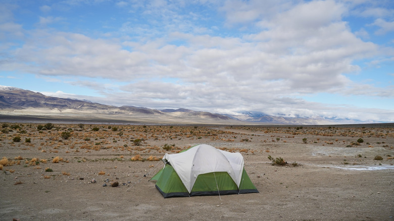 A green and white tent in Death Valley under a cloudy sky