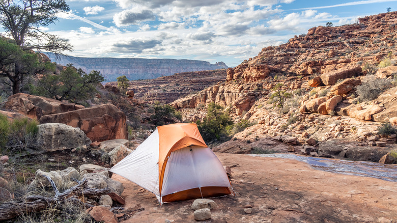 A white and orange tent in the Grand Canyon, surrounded by red rock