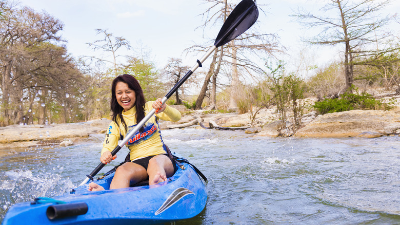 A woman smiling and kayaking