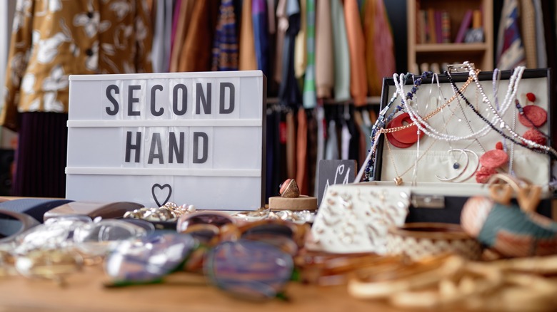 Sign with inscription Second Hand and jewelry case with vintage accessories at a thrift store.