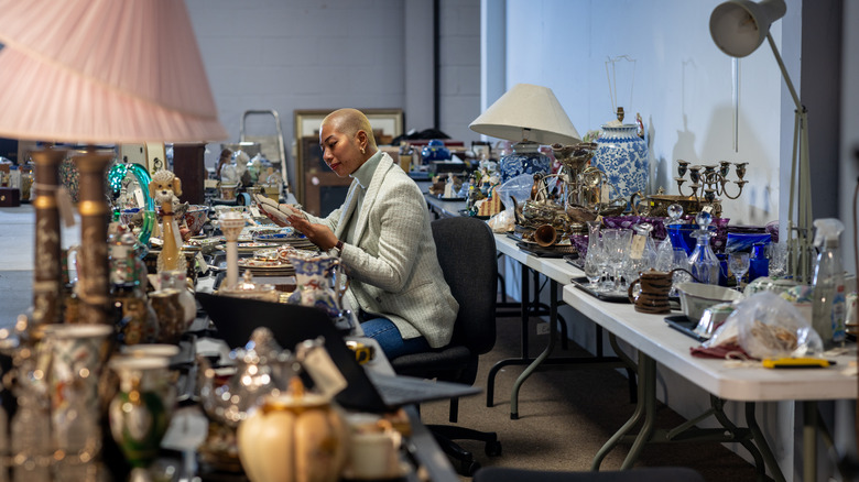 Female buyer holds item in hands and examines product in an antique store.
