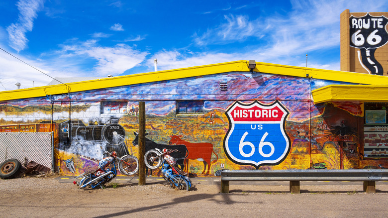 mural on wall of building in Seligman, Arizona along with Route 66 signs