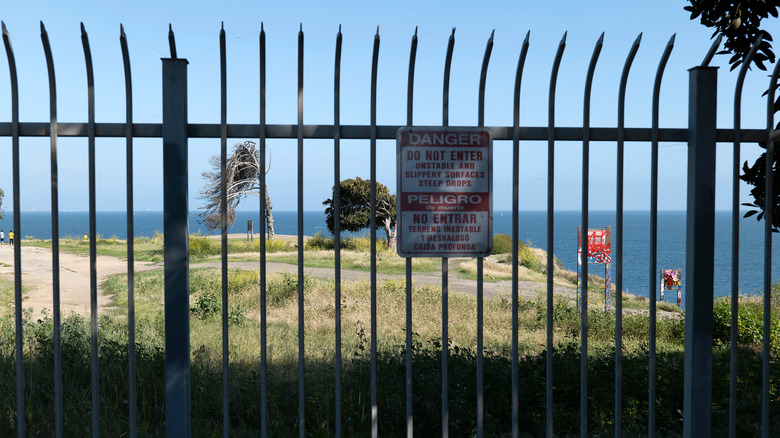 Gate with warning sign in English and Spanish blocking access to Sunken City in San Pedro, California