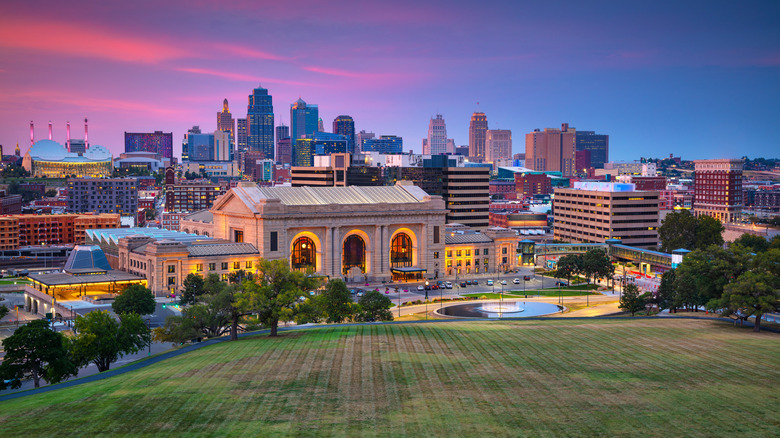 Front view of Union Station in Kansas City, Missouri with downtown in the background during the evening.