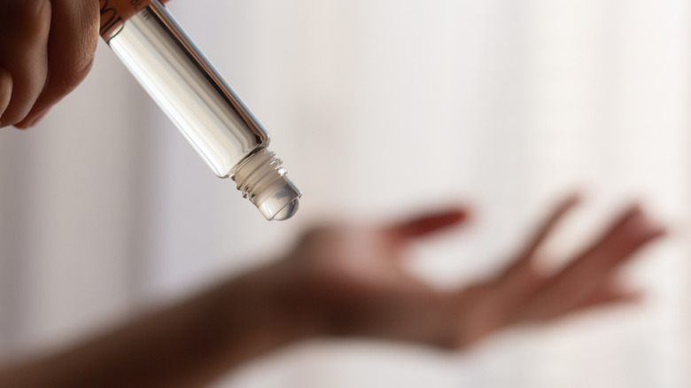 Woman applying perfume with a rollerball