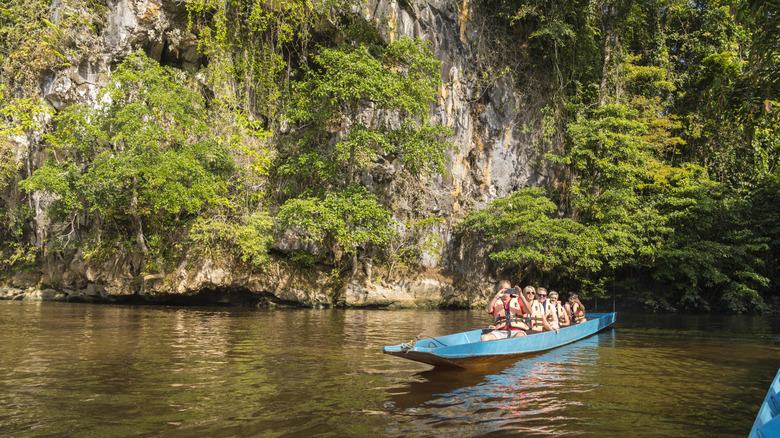 A small group of tourists on a long boat on a river in Borneo