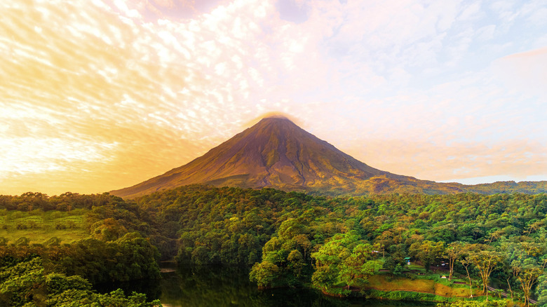 yellow skies play backdrop to volcano in the centre surrounded by lush forests