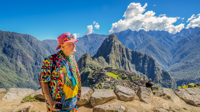 Old man in Inca constume with Machu Pichhu mountains in the backdrop