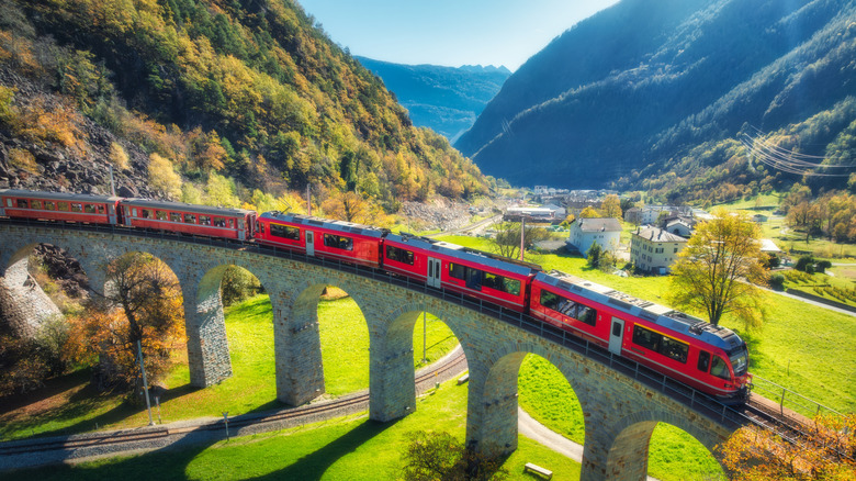 Aerial view of a red train snaking through Alpine scenery in Switzerland
