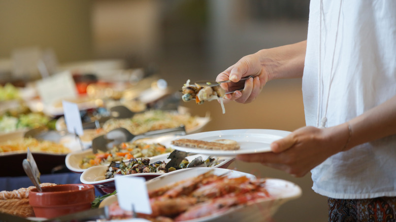Woman takes food from buffet