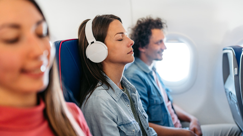 Woman in the middle seat with noise-cancelling earphones.