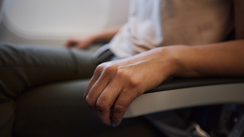 Close-up of a man's arm on an airplane armrest.