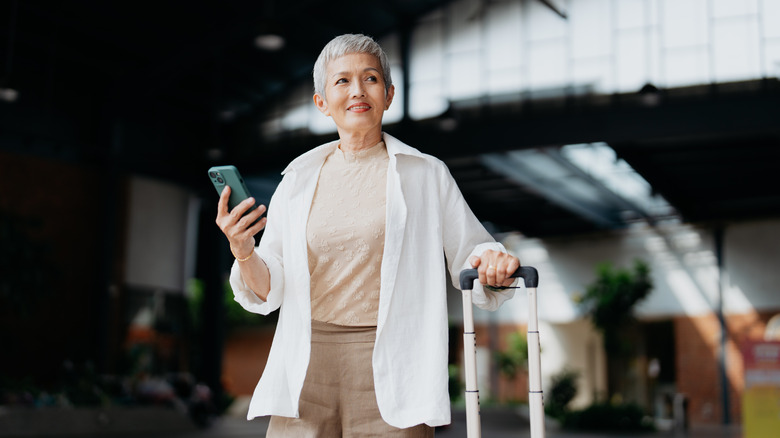 confident woman with suitcase and phone 