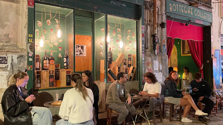 People sit at tables outside of a bar called Botteghe Colletti, Palermo, Sicily