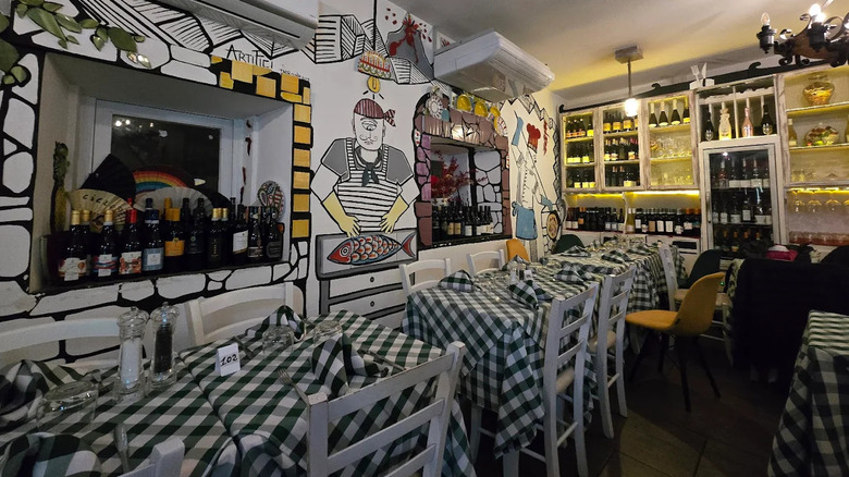 The interior of Daiquiri, a bar in Taormina with gingham-covered tables and wine on many shelves