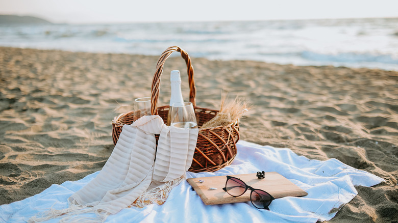 Two glasses of champagne and sunglasses in a picnic basket against the beach and the sea, Keansburg Beach, Raritan Bay