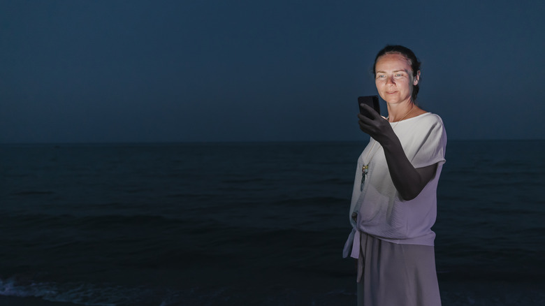Woman consulting her phone on a dark beach