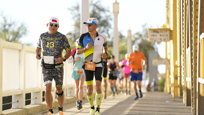 Marathoners run across yellow bridge
