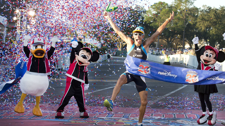 Donald Duck, Mickey Mouse, a runner, and Minnie Mouse celebrating in confetti at marathon finish