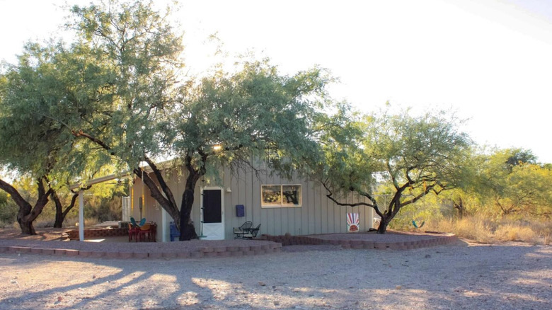 Gray ranch house shaded by trees