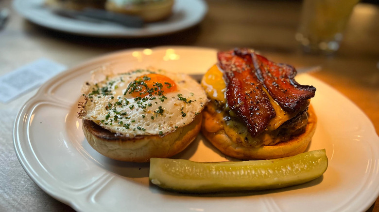 Cheeseburger with fried egg, bacon, and pickle spear from Au Cheval