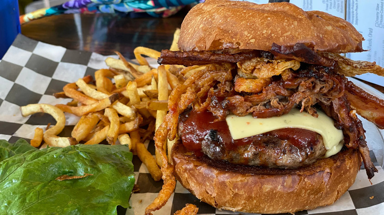 Burger with cheese, barbecue sauce, bacon, and fried onion, with fries from Stacked STL