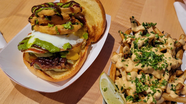 Burger with fried egg, onion rings, and herb sauce, and loaded fries from Lexie's Joint