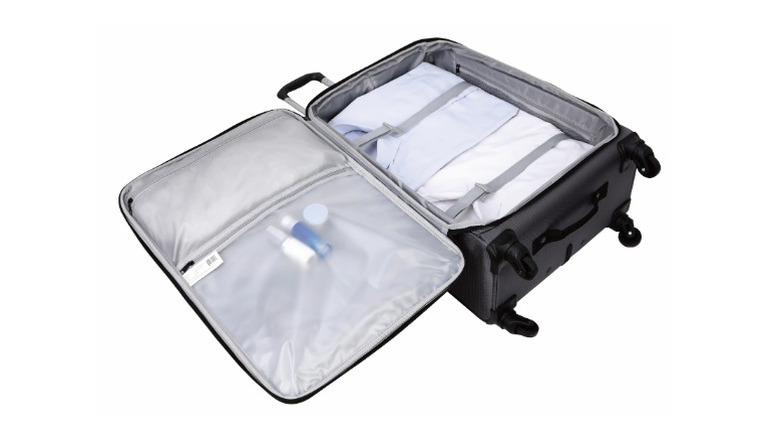 soft suitcase on a white background is open to show garments inside