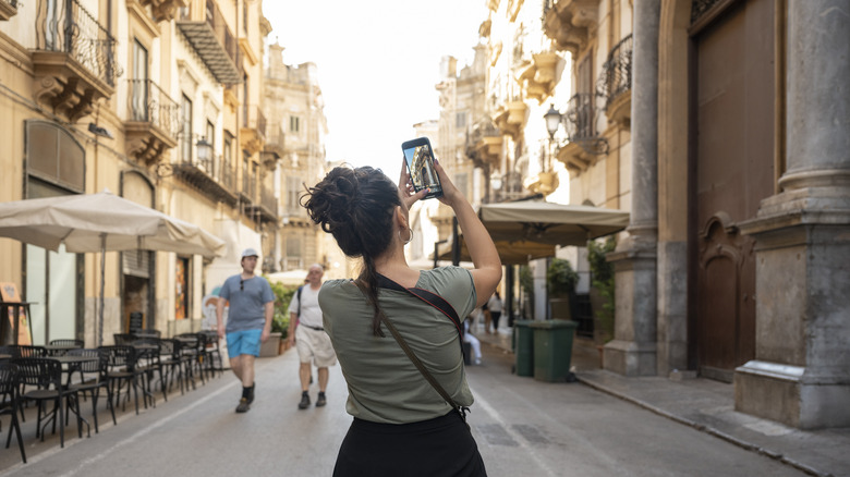 A woman snaps photo on street