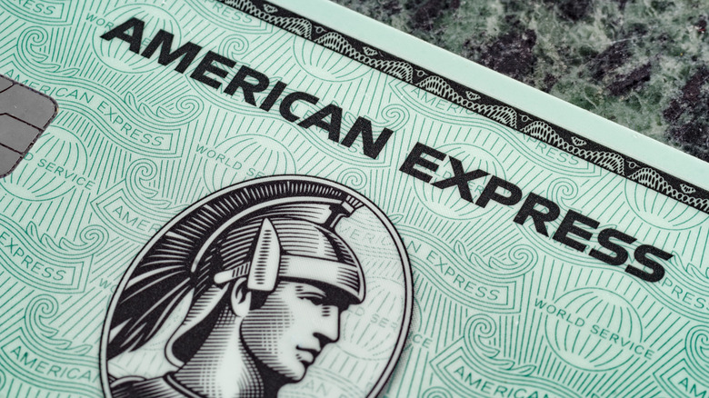 Close-up of a sample of an American Express credit card, and a person's hand holding it