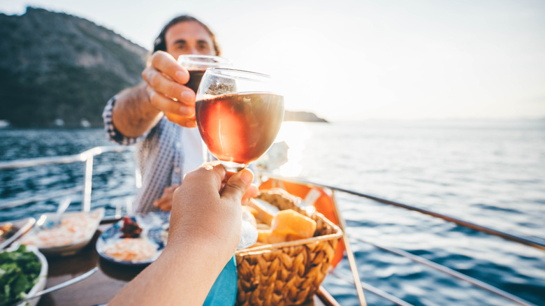 Close-up of couple toasting wine glasses on a cruise ship on open water