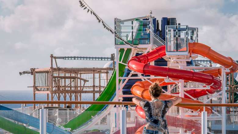 A woman looks out over the deck of  ship at a network of brightly colored waterslides