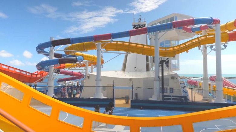 Red, yellow, and blue watertubes entangle and arch over the top deck of a Royal Caribbean ship
