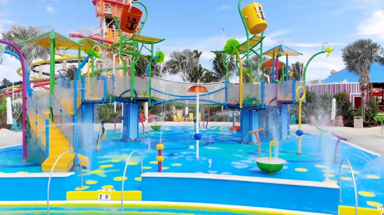 WaLarge yellow bucket in the middle of a very colorful waterslide complex on the top deck of a ship