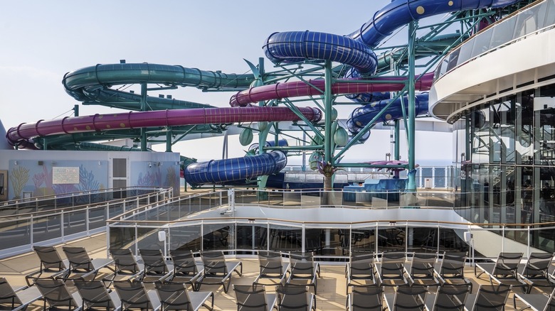 Huge blue and pink watertubes of a waterslide tower over the deck of a ship