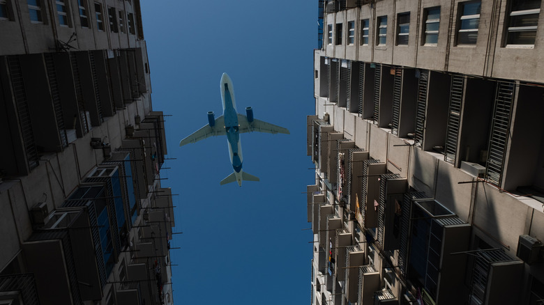 A plane flying above two apartment complexes with blue skies