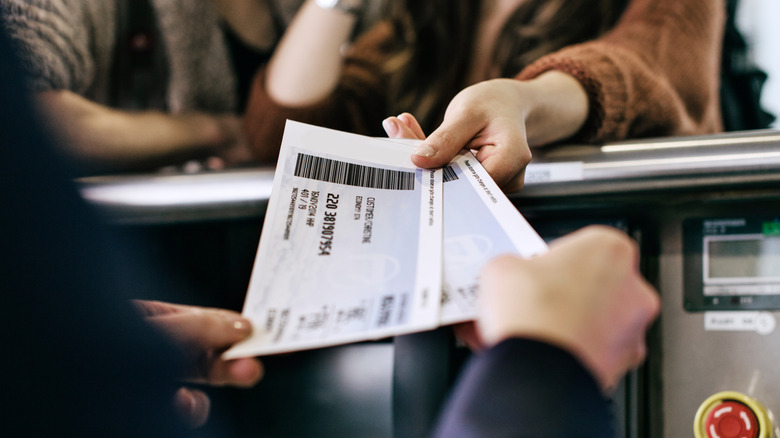 A gate attendant and a passenger looking at boarding tickets