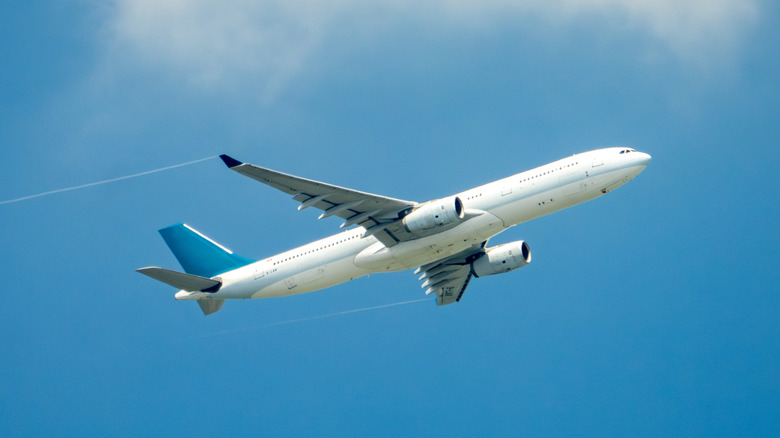 A plane flying in the blue sky with a hint of a cloud at the top