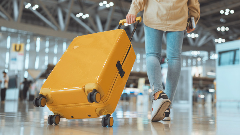 Person pulling a bright yellow suitcase behind them in an airport