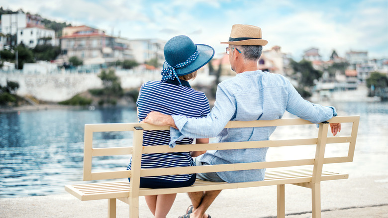 Senior couple sitting on a bench overlooking the water in Greece