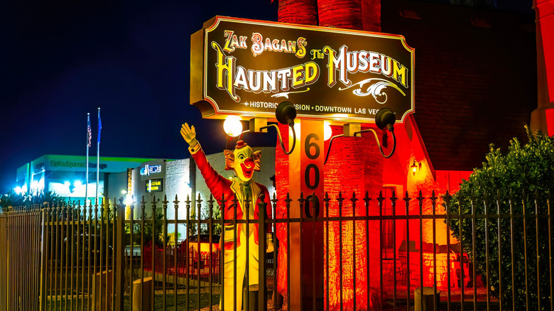 A clown statue next to a sign for Zak Bagans' The Haunted Museum at night