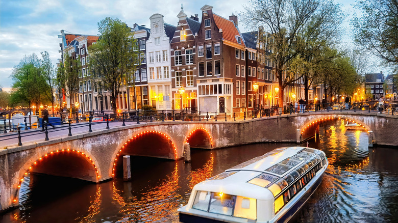 A boat along an Amsterdam canal with bridges and buildings in backdrop