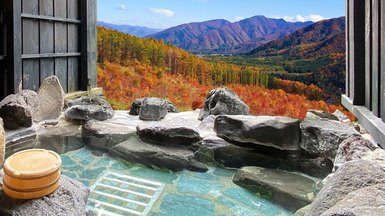 Thermal pool overlooking mountains with orange autumn trees.