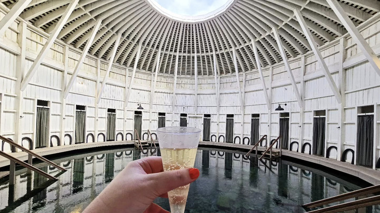 Hand holding glass of champagne in front of a hot spring pool