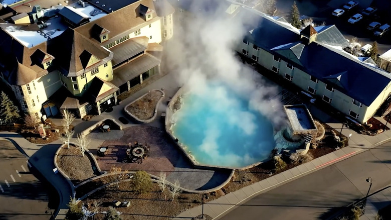 Aerial view of resort buildings and steaming hot springs pool.