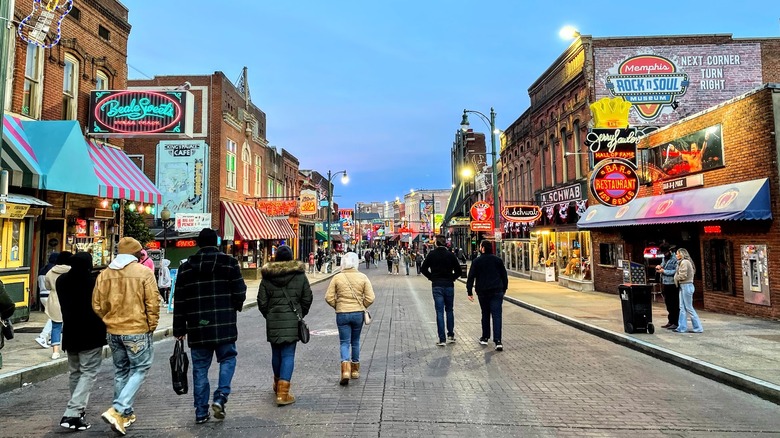 pedestrians on Beale Street full of neon signs and brick buildings