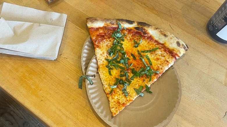 A slice of pizza from Audrey Jane's Pizza Garage sitting on a table