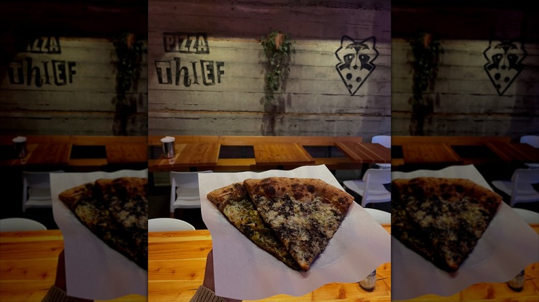 Woman holding two slices of pizza at Pizza Thief