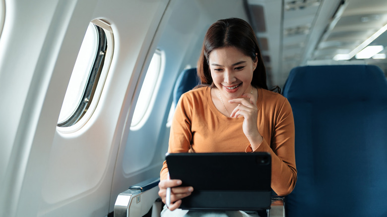 A woman using a tablet on a plane