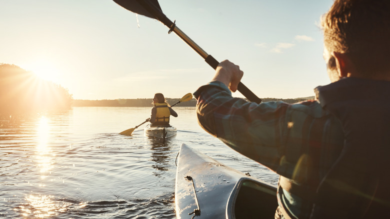 A young couple kayaking on a river at dusk